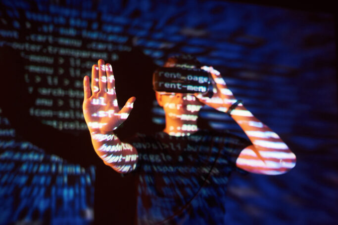 Double exposure of a caucasian man and Virtual reality headset is presumably a gamer or a hacker cracking the code into a secure network or server, with lines of code Segurança de rede